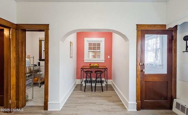 foyer with arched walkways, visible vents, light wood-style flooring, and baseboards