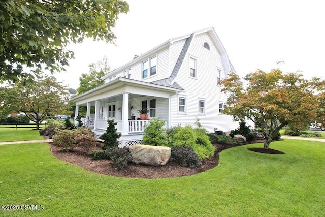 view of side of property with a porch, a lawn, and a gambrel roof