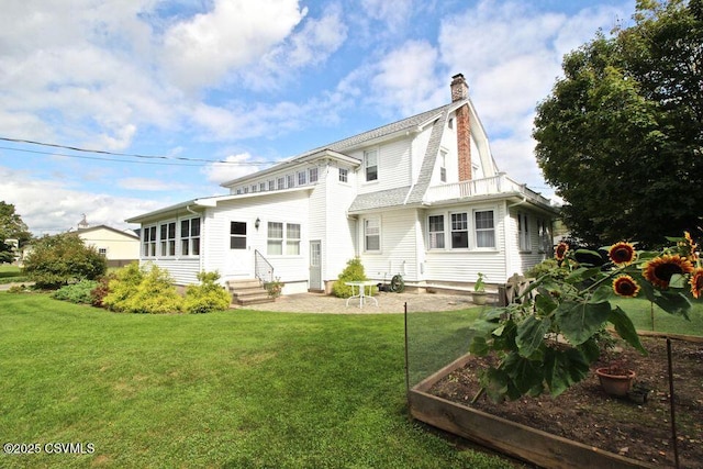 rear view of property with a chimney, a lawn, a gambrel roof, entry steps, and a garden