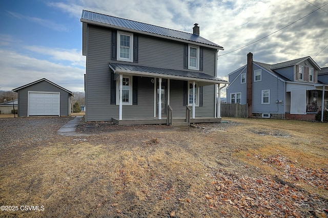 traditional home with an outbuilding, a chimney, covered porch, metal roof, and a garage