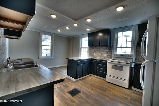 kitchen with visible vents, backsplash, a sink, white appliances, and a peninsula