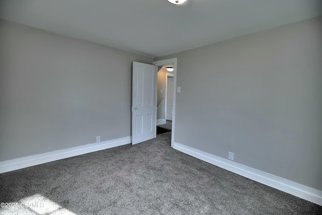 empty room with dark colored carpet and baseboards