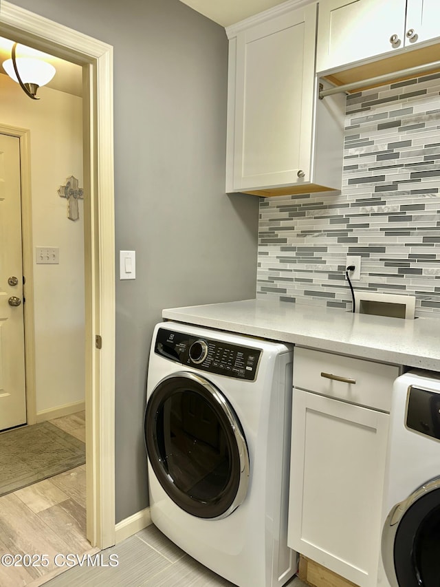 laundry room with cabinet space, baseboards, and washer / clothes dryer