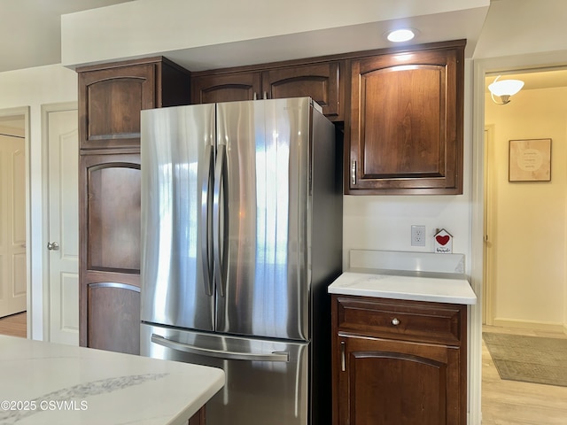 kitchen featuring dark brown cabinetry, light wood-style flooring, and freestanding refrigerator