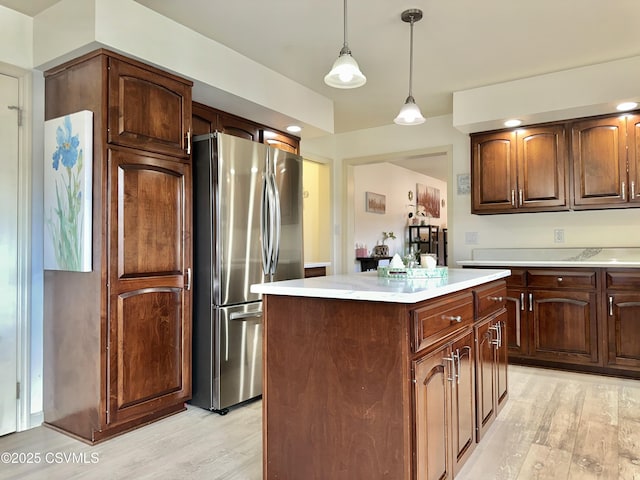 kitchen with a center island, decorative light fixtures, light countertops, light wood-style floors, and freestanding refrigerator