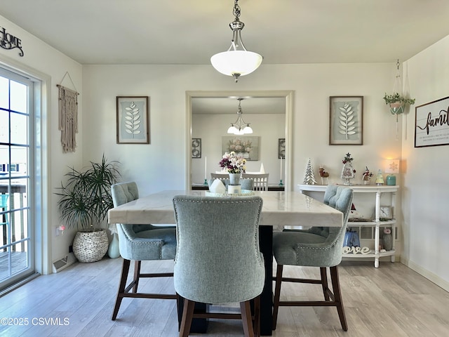 dining area with light wood-style floors, visible vents, and baseboards