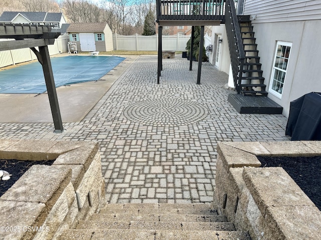 view of pool featuring a patio, a storage unit, stairway, a fenced backyard, and an outdoor structure