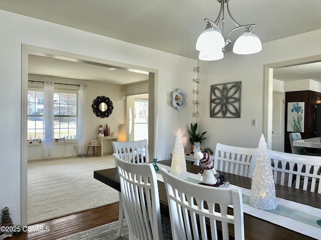 dining area with a notable chandelier, plenty of natural light, and wood finished floors