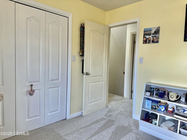 bedroom with a closet, light carpet, and baseboards