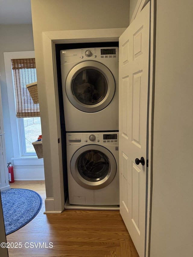 laundry room with stacked washer / dryer, laundry area, and wood finished floors