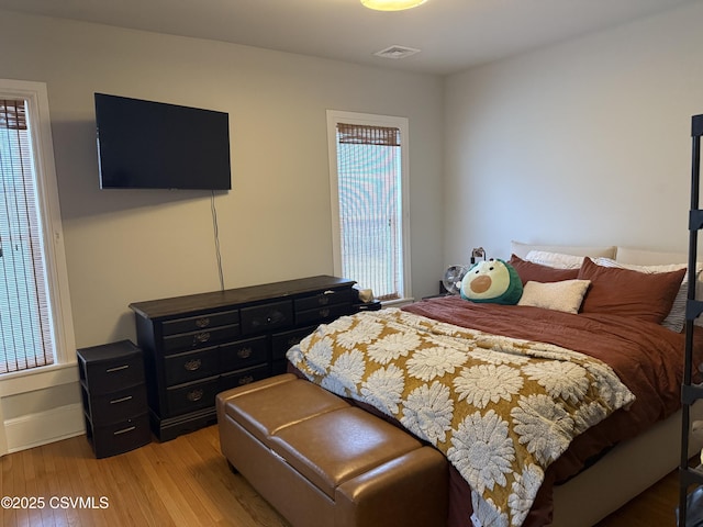 bedroom with light wood-type flooring, baseboards, and visible vents