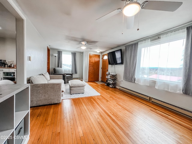 living area featuring light wood finished floors, a baseboard radiator, and a ceiling fan