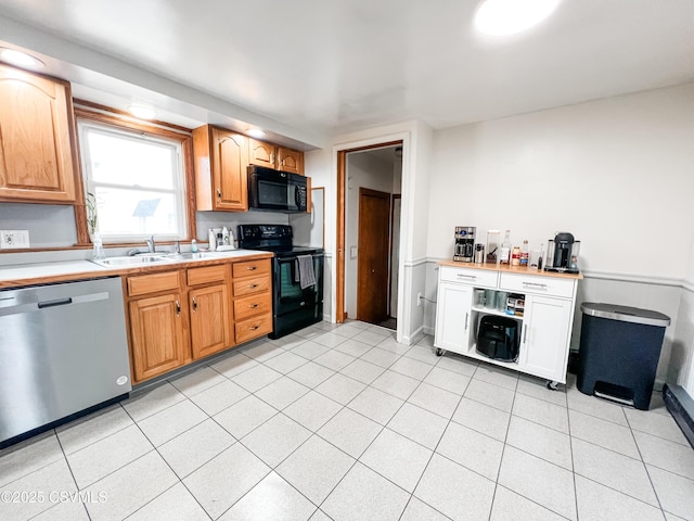 kitchen with light tile patterned floors, black appliances, a sink, and light countertops