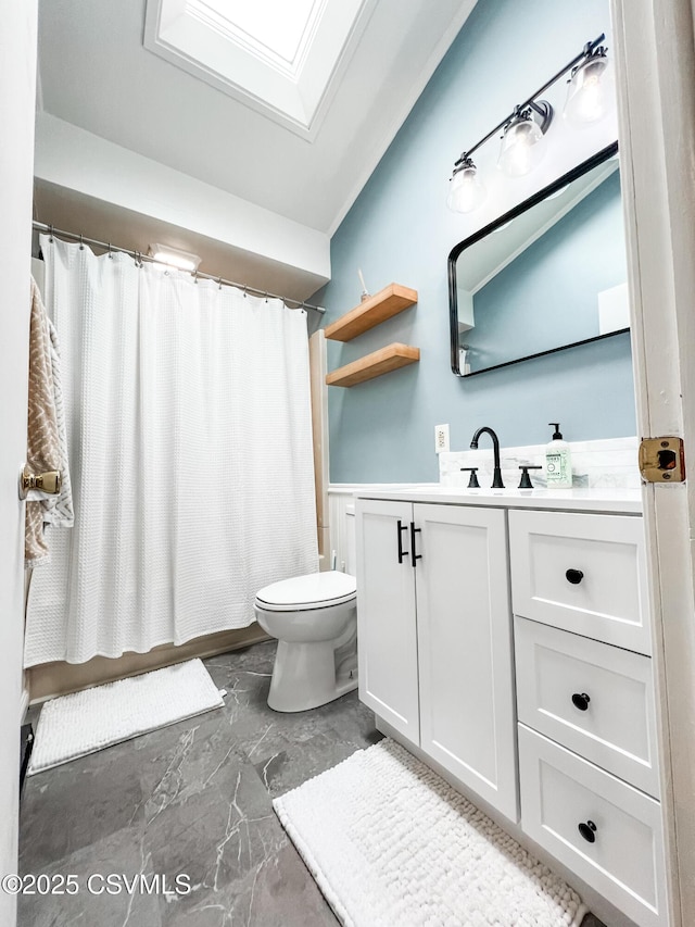 bathroom featuring toilet, a skylight, vanity, marble finish floor, and a shower with curtain