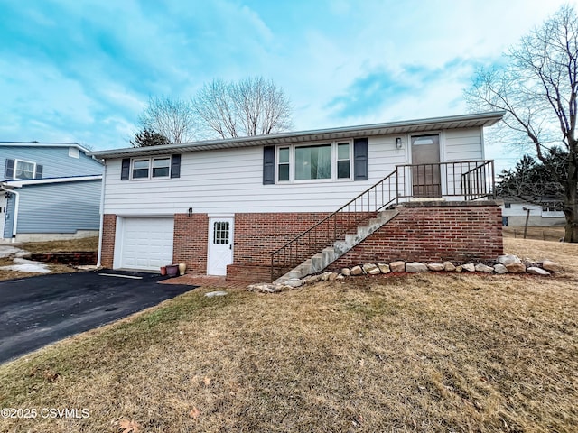 view of front of house featuring driveway, a front yard, a garage, and brick siding