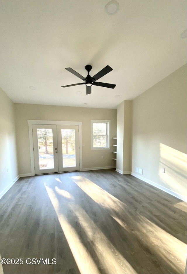 empty room with french doors, ceiling fan, baseboards, and wood finished floors