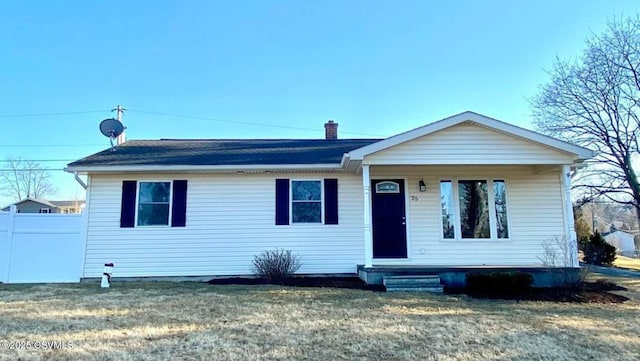 view of front of house featuring fence, a chimney, and a front lawn