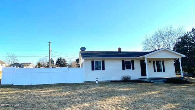 view of front of house with a chimney, fence, and a front yard