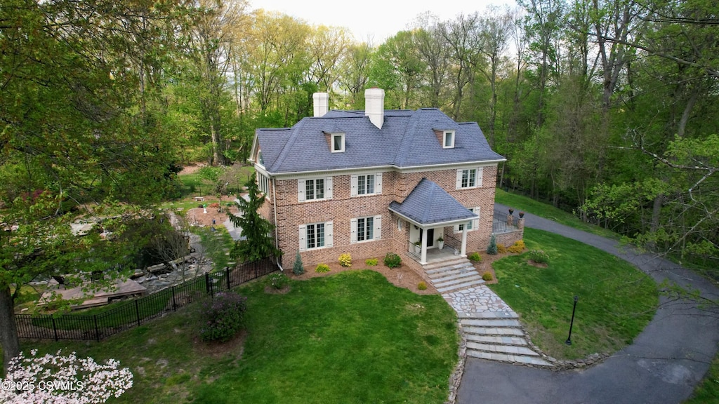 view of front of house with a front yard, brick siding, fence, and a chimney