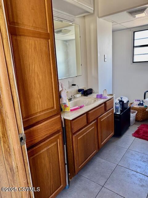 bathroom with tile patterned flooring, visible vents, vanity, and a drop ceiling