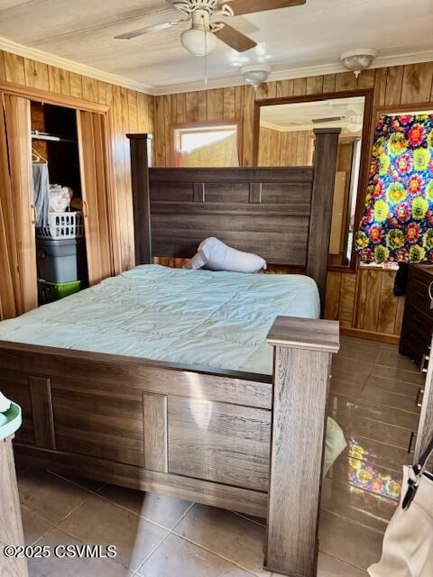 tiled bedroom featuring ornamental molding, wooden walls, and a ceiling fan