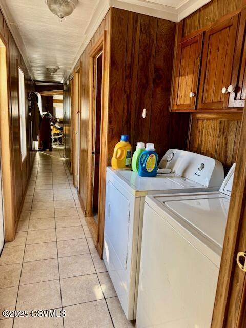 washroom with cabinet space, independent washer and dryer, wooden walls, and light tile patterned floors