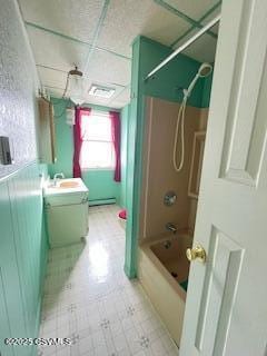 full bathroom with a drop ceiling, a baseboard heating unit, vanity,  shower combination, and tile patterned floors