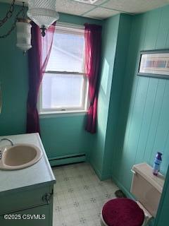 bathroom with a drop ceiling, a baseboard radiator, wooden walls, vanity, and tile patterned floors