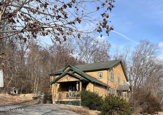 rustic home with covered porch and aphalt driveway