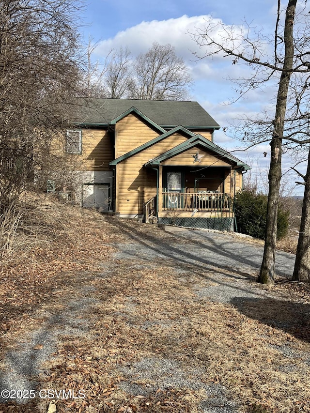 rustic home featuring covered porch and driveway