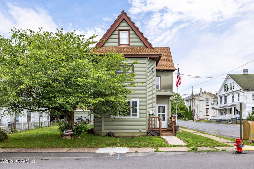 view of front facade featuring a shingled roof, a residential view, and fence