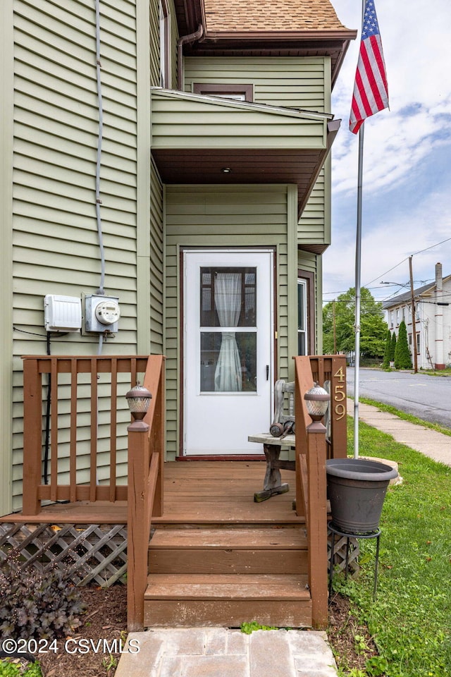 view of exterior entry featuring roof with shingles