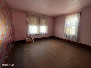 spare room featuring baseboards and hardwood / wood-style flooring