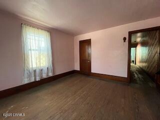 spare room featuring wood finished floors and baseboards