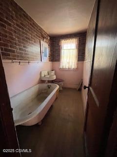 full bathroom featuring brick wall, a bathtub, and toilet