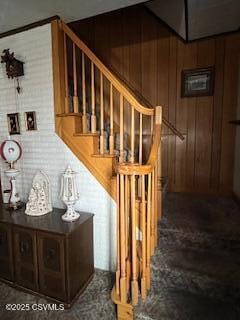 stairway featuring wooden walls