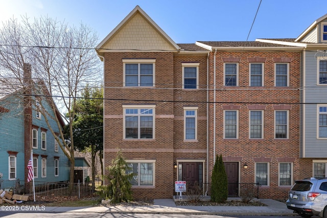 townhome / multi-family property featuring brick siding and fence