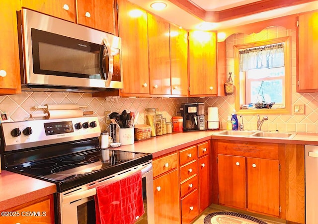 kitchen featuring stainless steel appliances, light countertops, a sink, and tasteful backsplash