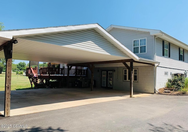 exterior space with concrete block siding, french doors, a carport, and a front yard