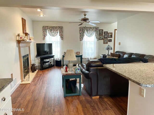 living area with ceiling fan, dark wood-style flooring, a fireplace, and visible vents