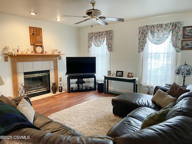 living room with a fireplace, a ceiling fan, and wood finished floors