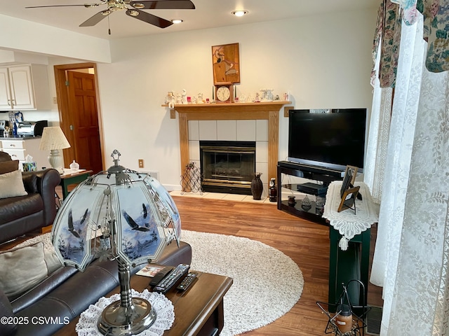 living area featuring a tile fireplace, ceiling fan, recessed lighting, and wood finished floors