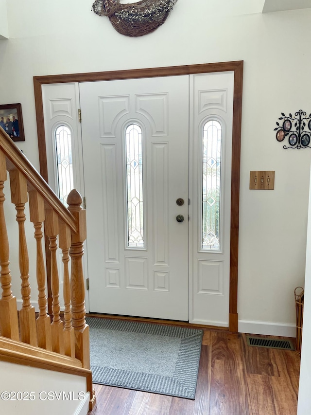 foyer entrance featuring a wealth of natural light, stairway, wood finished floors, and visible vents