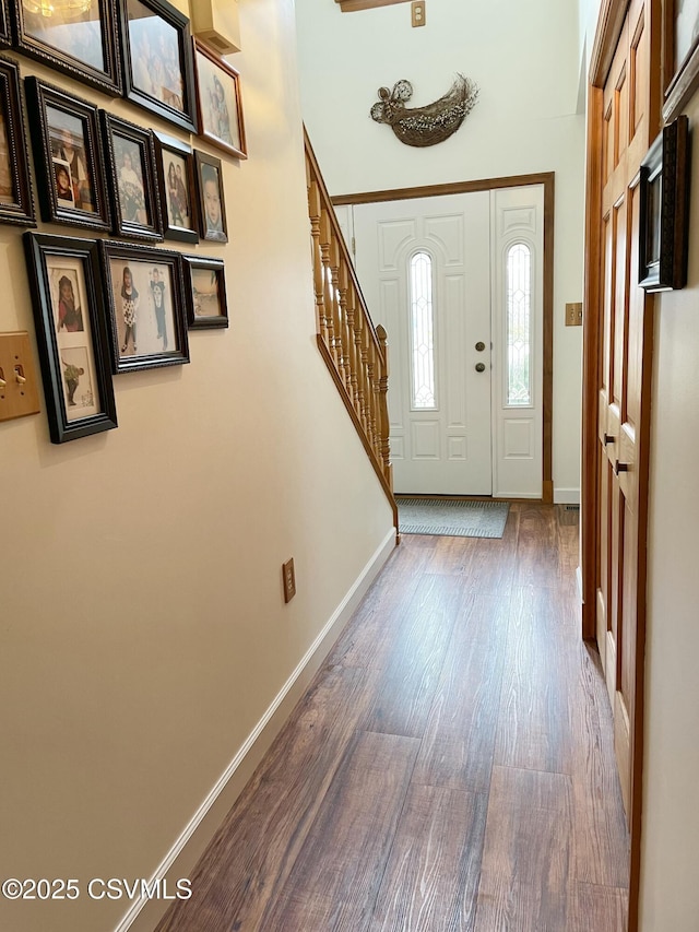 entryway with stairway, baseboards, and wood finished floors