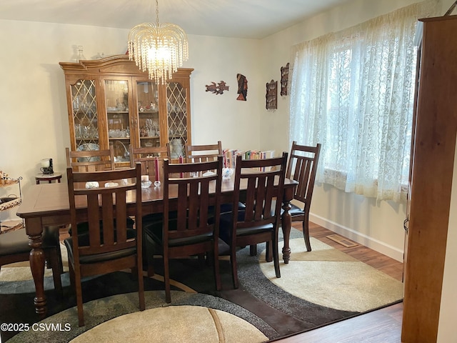 dining area with a chandelier, visible vents, baseboards, and wood finished floors