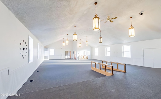 interior space with high vaulted ceiling, wainscoting, and a textured ceiling