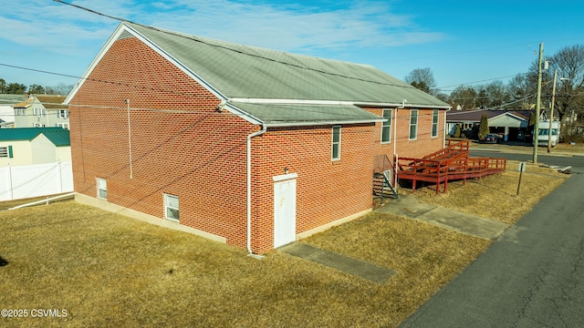 view of home's exterior with brick siding, a lawn, and fence