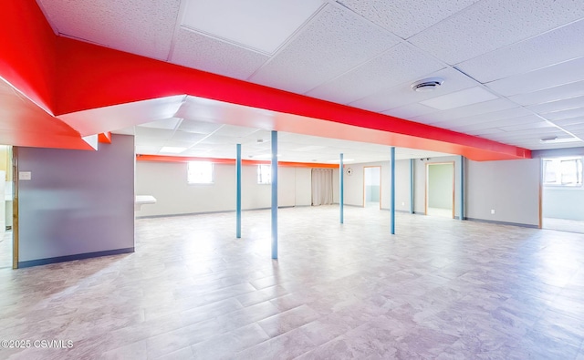 below grade area featuring a drop ceiling, baseboards, and visible vents