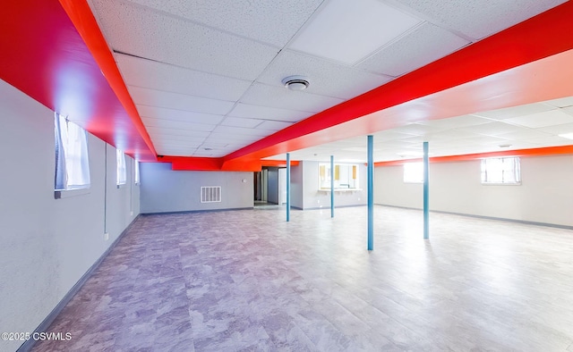 below grade area featuring a drop ceiling, visible vents, and baseboards