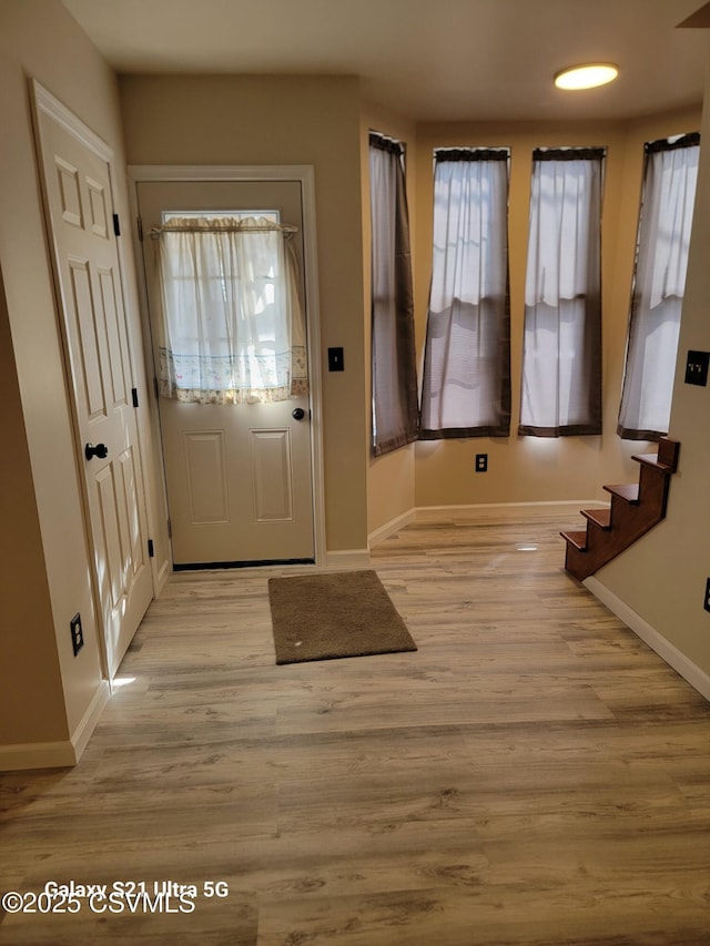 entryway with stairway, baseboards, and light wood finished floors